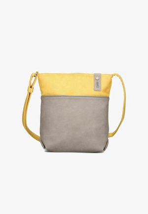 Sac bandoulière bicolore avec une partie supérieure jaune, une partie inférieure grise, une sangle jaune réglable et une petite étiquette en tissu en haut à droite.