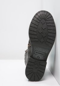 Černá kožená podrážka boty s výrazným vzorem tread, gumová konstrukce, značka logo a jemné detaily šití.