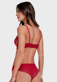 Soutien-gorge en dentelle rouge et slip assorti ; tissu transparent, bretelles réglables et fermeture à agrafes ; motifs floraux sur le soutien-gorge pour une touche supplémentaire de détails.