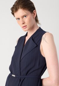 Vestido sin mangas de rayas marineras con cuello muesca, cinturón en la cintura ajustado y tela lisa. Brillo sutil con un diseño minimalista.