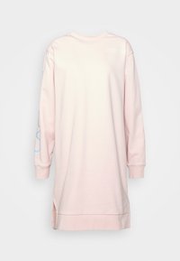 Růžové oversized šaty z mikiny s dlouhými rukávy, kulatým výstřihem, bočními rozparky a modrým grafickým detailem na levém rukávu.