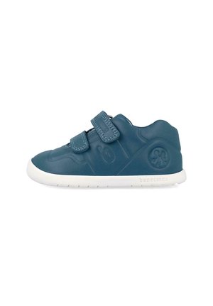 Zapatilla azul marino para niños con dos tiras de velcro y suela blanca, con logo en relieve y detalle de flor en el talón.