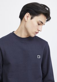 Navy Sweatshirt aus Baumwollmischgewebe. Mit Rundhalsausschnitt, gerippten Bündchen und einem kleinen gestickten Logo auf der Brust. Glatte Textur.