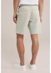 Light green linen blend shorts with a textured pattern, elastic waistband, two back pockets, worn with white sneakers.