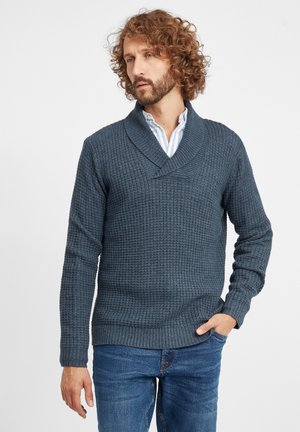 Knitted dark blue sweater with a crossover collar, textured pattern, ribbed cuffs, and hem; worn over a light, striped shirt.