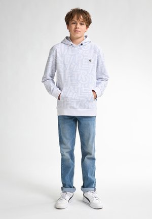 Witte hoodie met lichtblauwe tekstpatronen, voorzak en trekkoordkap, gecombineerd met lichtblauwe jeans en witte sneakers.