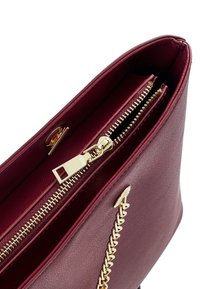 Sac à main en cuir bordeaux avec fermeture éclair dorée et détail de chaîne dorée, vu de dessus mettant en évidence les compartiments intérieurs.