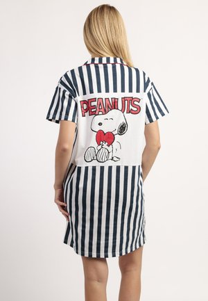 Mujer con vestido de manga corta a rayas azules y blancas, con un dibujo en la espalda de Snoopy sosteniendo un corazón rojo y la palabra "PEANUTS" encima.