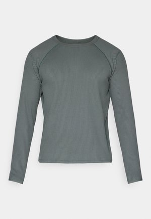 T-shirt à manches longues de couleur vert foncé, fabriqué en matériau texturé et côtelé, avec un col rond et des manches raglan.