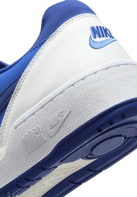 Sapatilha Nike com um esquema de cores branco e azul, parte superior em sintético suave, sola texturizada e marcas em relevo "FORCE" e "NIKE".