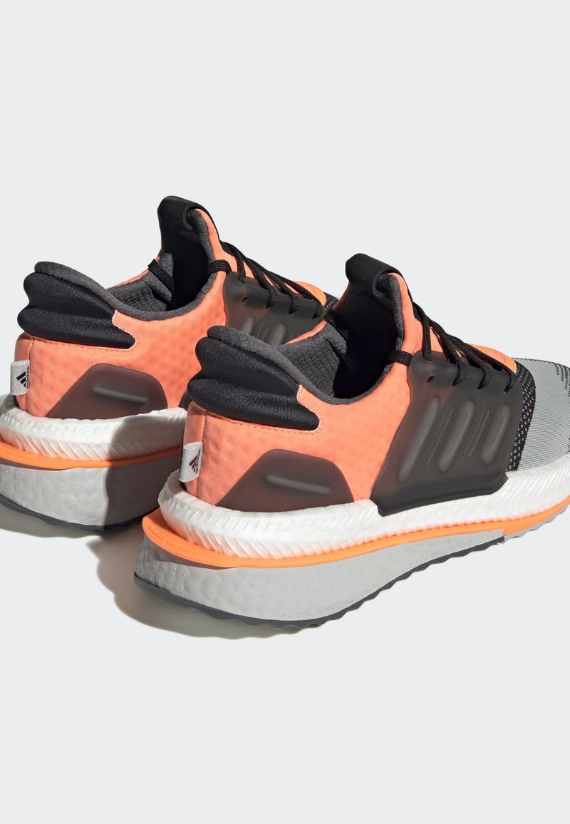 Zapatillas deportivas con un upper transpirable en melocotón y negro, acentos grises, material texturizado y una suela blanca acolchada.