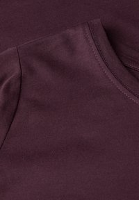 Bordeaux t-shirt met een soepele, ribbelige textuur. Heeft een ronde halslijn en zichtbare stiksels langs de randen.