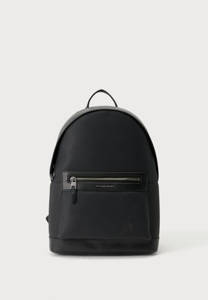 Sac à dos Michael Kors en cuir noir avec une poche zippée à l'avant et une poignée de transport supérieure sur un fond clair uni.