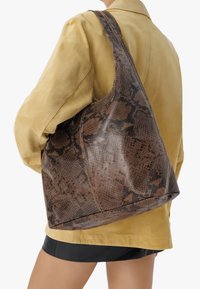 Torebka na ramię w brązowy wężowy wzór z teksturowanym, błyszczącym wykończeniem; zaprojektowana z jedną szeroką rączką, miękka i luźna w kształcie.