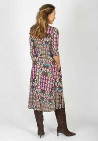 Flerfärgad klänning med diamantmönster, med trekvartsärmar, en A-linjepassform och knälång fåll. Bärs med bruna stövlar över knät.