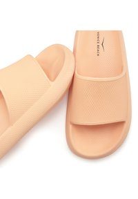 Peach-colored rubber slides with a textured strap and dotted surface. Features a wide opening and a patterned sole for grip.
