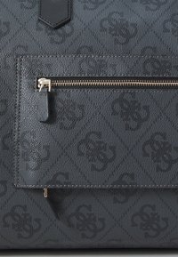 Borsa nera con texture, caratterizzata da un motivo a diamante, una tasca frontale con cerniera dotata di hardware dorato e un accento in pelle a contrasto.