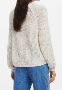 Pull en maille épaisse de couleur blanc cassé avec des éclats multicolores. Doté de poignets et d'un ourlet côtelés, coupe ample et tissu texturé.