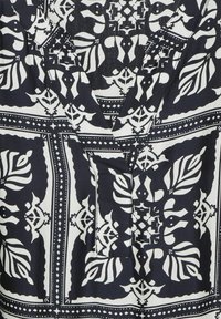 Navy- und weiß gemusterter Stoff mit floralem und geometrischem Design und V-Ausschnitt. Glatte Textur mit leicht glänzender Optik.