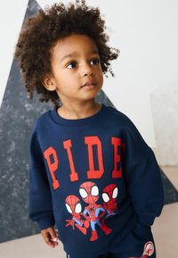 Tumed sinine kraepluus, millel on punane "PIDE" tekst ja kolm Spider-Man graafikat. Tal on ümar krae, pikad varrukad ja pehme tekstuur.