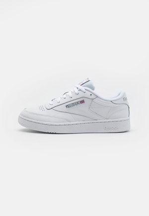 Witte lage leren Reebok sneaker met vetersluiting, geperforeerde neus en Reebok-logo met Britse vlag op het zijpaneel.