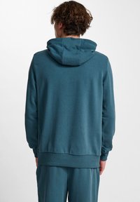 Felpa blu verde realizzata in tessuto morbido, dotata di cappuccio con cordino, maniche lunghe e orlo a coste. Design semplice senza loghi visibili.