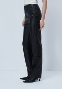 Black leather wide-leg pants with a smooth texture, featuring front pockets and a high waist, paired with black pointed-toe heels.