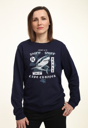 Dunkelblaues Sweatshirt mit einem Grafikdesign eines Hais und weißem sowie hellblauem Text, der "SHARKY & CO. SNIFF . SNIFF SCALE 754-67 CAPE CRUISER." lautet.