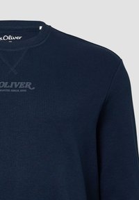 Felpa blu navy con collo a girocollo a coste, texture morbida e stampa del logo sul davanti. Presenta un design semplice e casual con dettagli cuciti.