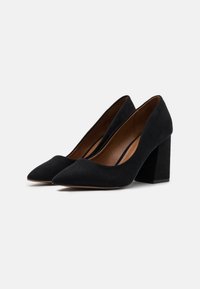 Schwarze Wildleder-Pumps mit spitzem Zehenbereich und dicker Blockabsatz. Glatte Textur mit matter Oberfläche, versehen mit einem tief ausgeschnittenen Schaftdesign.