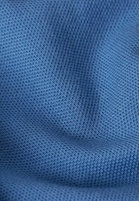 Blått texturerat tyg med ett nätmönster, som har en jämn, vävd yta. Tyget har ett enhetligt, medeltungt utseende.