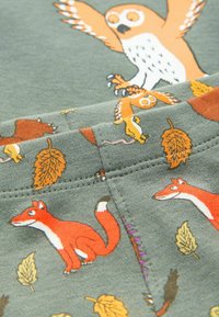 Cotton fabric in olive green with orange owl design and playful animal patterns featuring foxes and leaves, soft texture, stitched details.