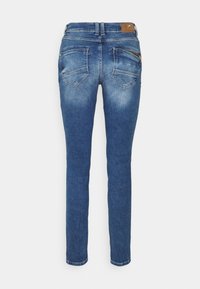 Smala blåjeans i denimmaterial med blekningsdetaljer, två bakfickor och en dragkedjeficka på högersidan. Brunt läderaccent vid midjan.