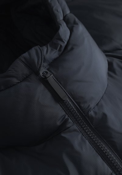 Close-up of a black padded jacket showing a partially zipped black zipper and fabric texture.
