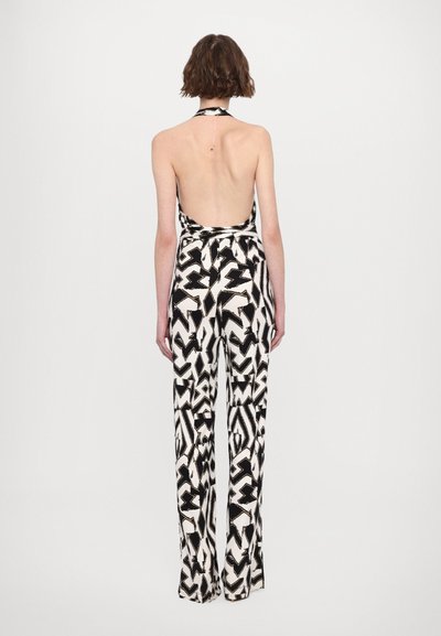 Achteraanzicht van een zwart-witte jumpsuit met een halternek, brede benen en een open rug, voorzien van geometrische ontwerpen.