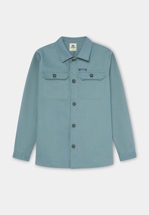 Camisa azul claro abotonada, con dos bolsillos en el pecho con solapas, cuello redondo, mangas largas y dobladillo redondeado. Hecha de tela texturizada.