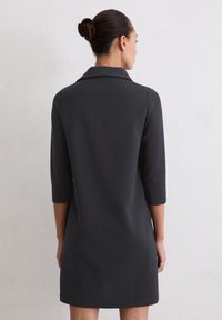 Ciemnoszara sukienka z kołnierzykiem, rękawami do połowy przedramienia i prostym krojem. Wykonana z gładkiej tkaniny z minimalnymi zdobieniami.