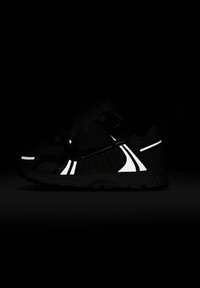 Sneaker noir avec accents réfléchissants blancs, tige en maille texturée, design élégant et semelle en caoutchouc. Présente un logo de marque visible.