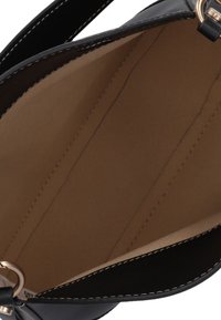 Zwarte handtas interieur met een glad, lichtbruin voering; voorzien van gelijkmatige stiksels en minimalistisch ontwerp; met een metalen accent.