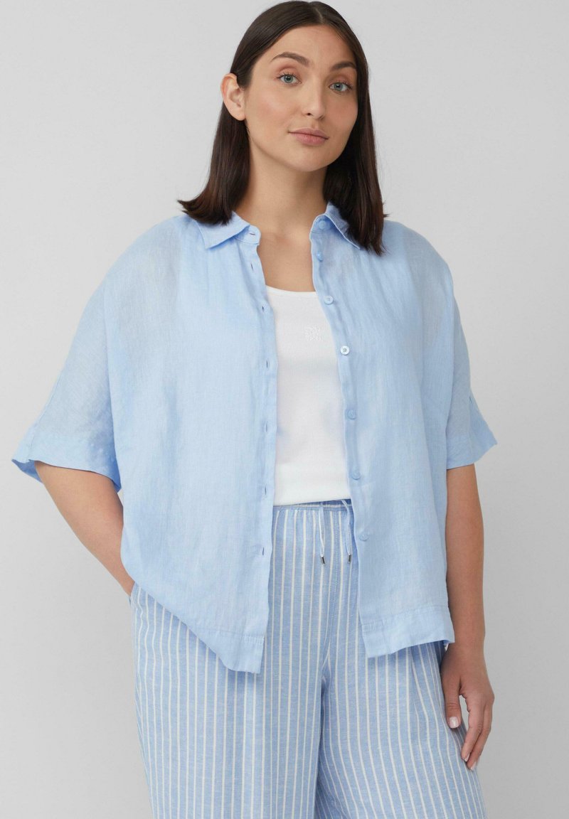 Lichtblauwe linnen oversized overhemd met korte mouwen, knopen aan de voorkant, gecombineerd met gestreepte lichtblauwe broek. Eenvoudig en casual ontwerp.