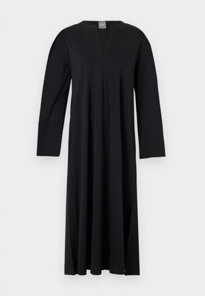Svart långärmad klänning med V-ringning, gjord av ett slätt tyg. Har sidoklipp, avslappnad passform och en sömlös axeldesign.