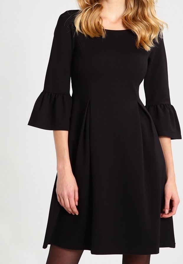 Robe noire à manches cloche trois-quarts, corsage ajusté et jupe évasée. Confectionnée dans une matière lisse avec des détails plissés.