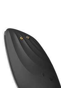 Svart ergonomisk groomingverktyg med böjd, ribbad design, har två guldaccenter och fina borst längs kanten för precision.