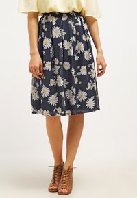 Spódnica do kolan w kwiaty z granatowym tłem i białymi oraz żółtymi stokrotkami, plisowany krój i lekka, teksturowana tkanina.