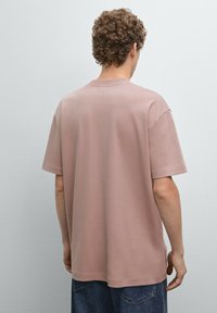T-shirt a maniche corte di colore rosa chiaro realizzato in tessuto morbido, con una vestibilità comoda e design con collo rotondo. Senza fantasie o dettagli visibili.
