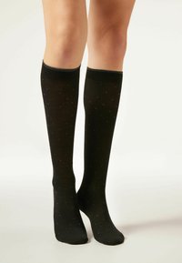 Knielange zwarte sokken van gladde stof, met een stippenpatroon in blauwe accenten. De bovenkant heeft een geribbelde boord voor extra comfort.