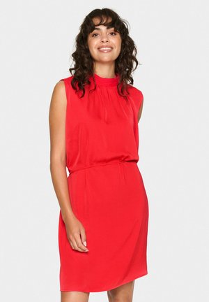 Punainen hihaton mekko, jossa on korkea kaula-aukko ja rypytetty yksityiskohta vartalon kohdalla. Pehmeä, sileä kangas rentoon istuvuuteen, loppuu polven ylle.
