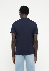 Marineblå, kortærmet t-shirt lavet af bomuld. Rund halsudskæring, tætsiddende pasform, glat tekstur og enkelt design uden mønstre eller grafik.
