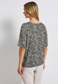 Top corto a maniche corte bianco e nero con motivo a strisce di zebra, vestibilità comoda, scollatura rotonda e tessuto morbido.
