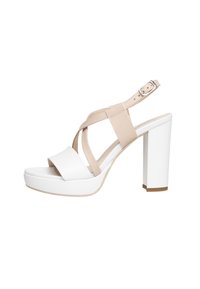 Sandalia de plataforma de tacón alto en color beige y blanco con una amplia correa frontal blanca y correas para el tobillo entrelazadas. Suela texturizada y tacón cuadrado.